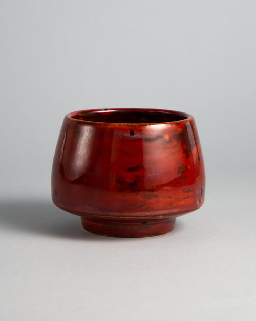 WINDY CUP 'TANGO', handmade stoneware cup without a handle by Studio 517. High-gloss deep red with orange tones where the light hits and darker oxblood brushstrokes around the base: the loudest cup on the table.