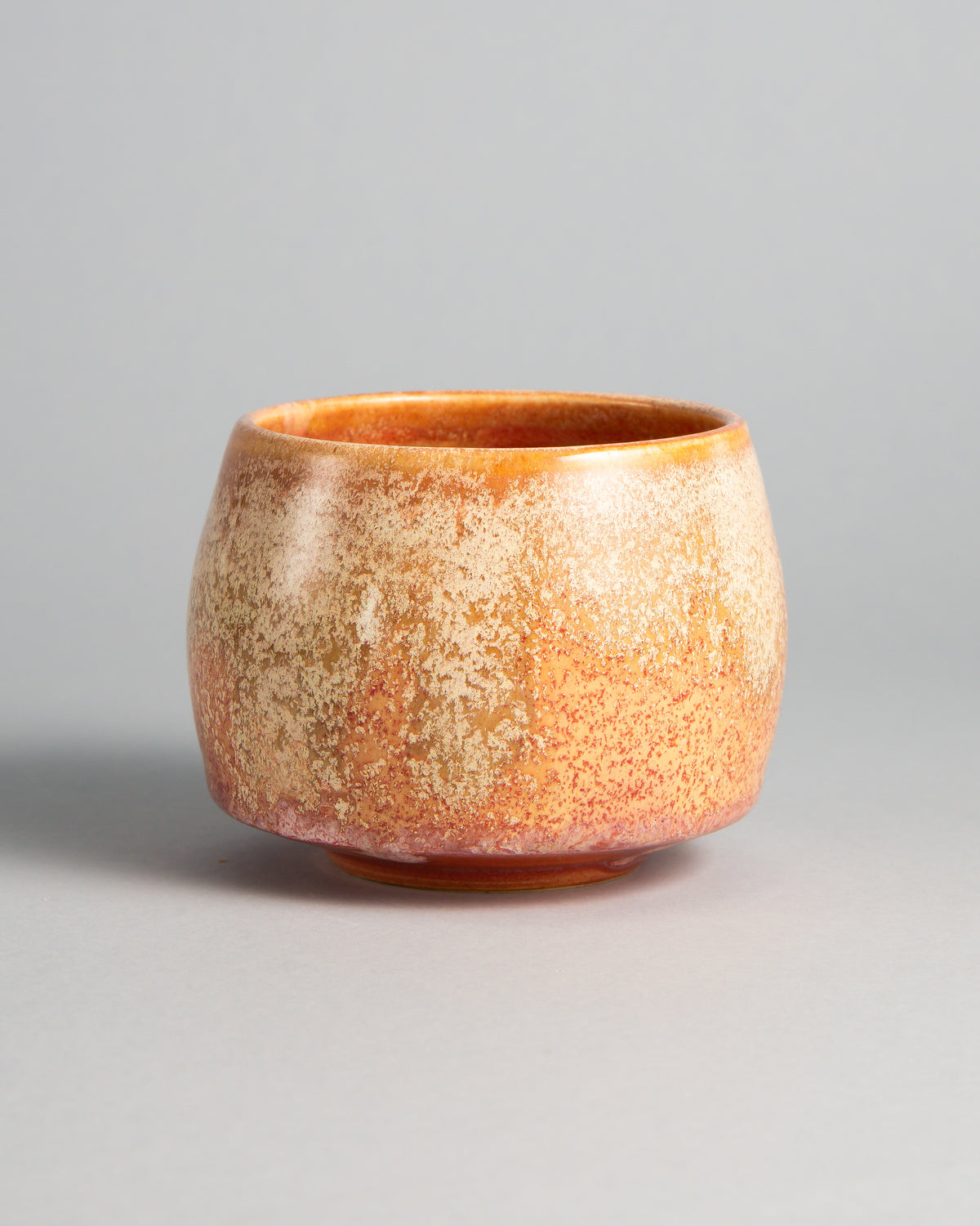 WINDY CUP 'CORAL', handmade stoneware cup without a handle by Studio 517. Satin coral orange covered in a fine cream speckle, denser near the top and thinner towards the foot, with a glossy orange rim.