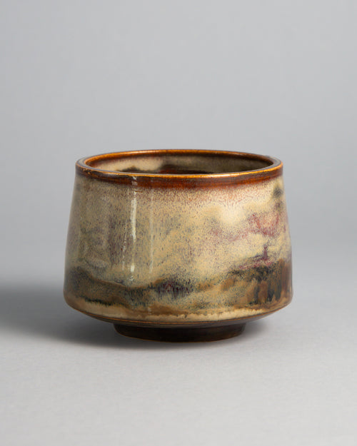 WINDY CUP 'STRATA', handmade stoneware cup without a handle by Studio 517. Horizontal bands of cream, pale sage, smoky lilac grey and earthy brown, with an amber rim and a dark foot, layered like rock built up over time.